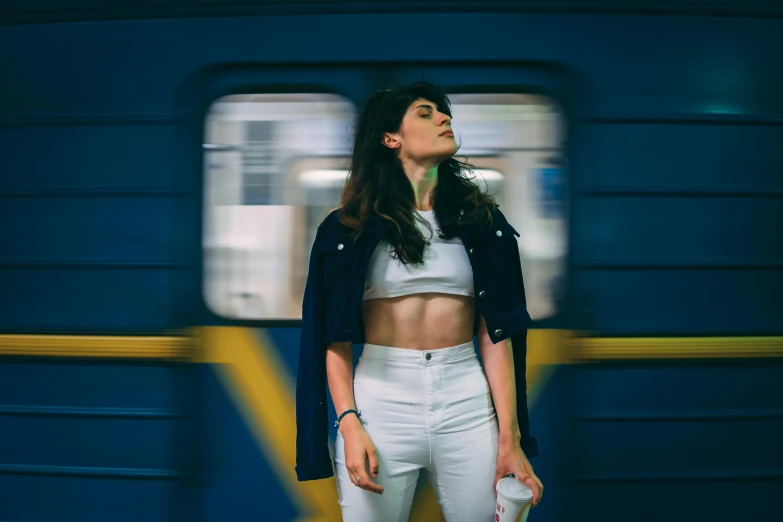 a woman standing next to a train with her hands behind her head