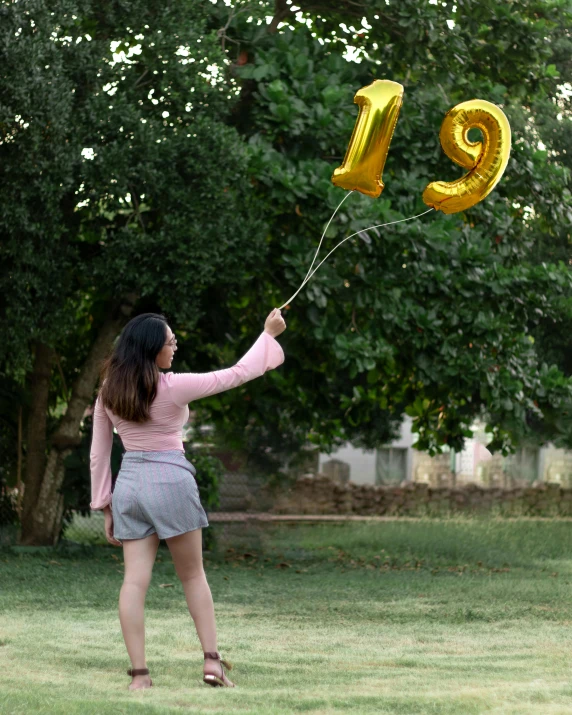 a woman in pink shirt holding onto yellow balloons