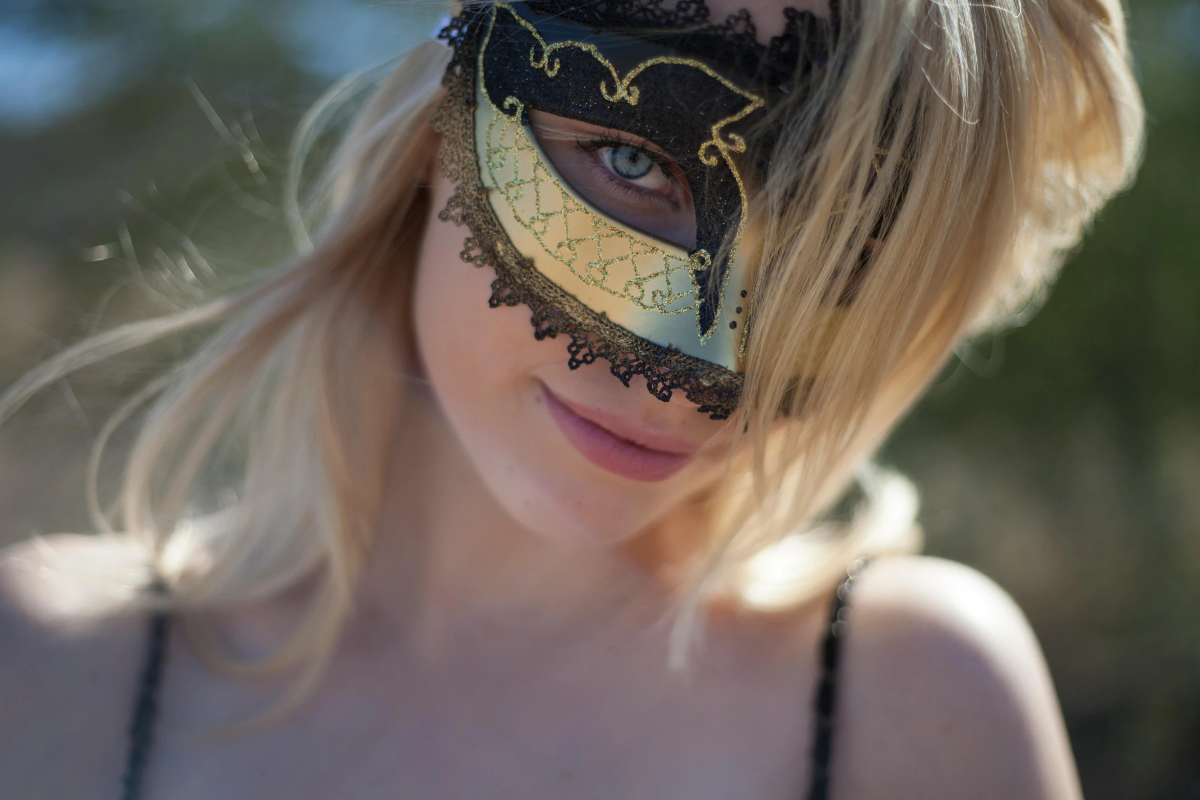 a woman with a black and gold mask is smiling