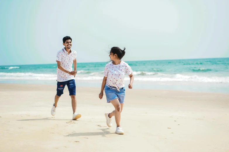a boy and a girl are running on the beach