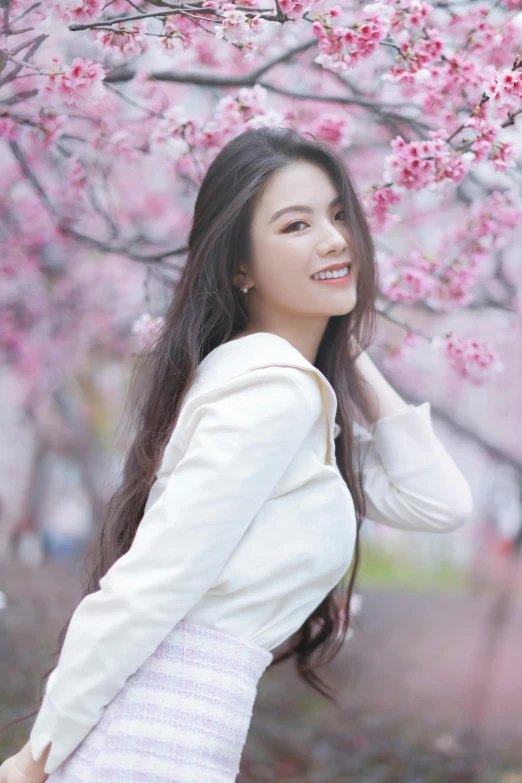 a woman poses under a cherry blossom tree