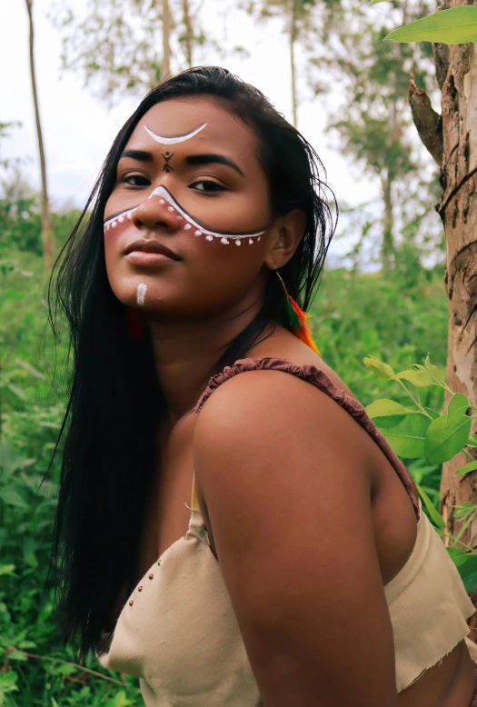 a  with white painted on her face next to a tree