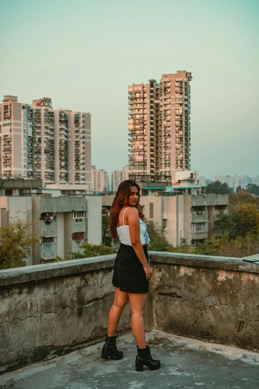 a woman standing on top of a ledge overlooking some buildings