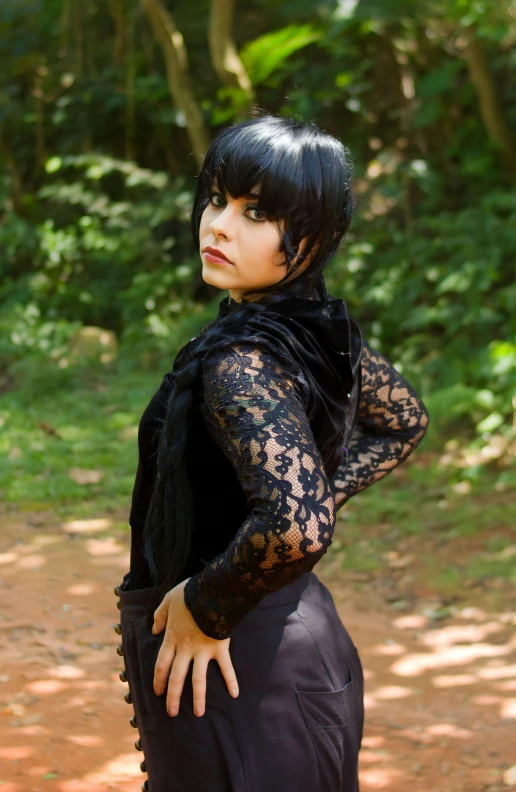 a woman in black dress with black gloves posing on a dirt road