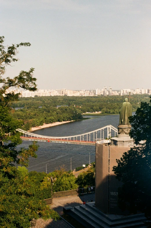 a statue standing on the edge of a building overlooking a river