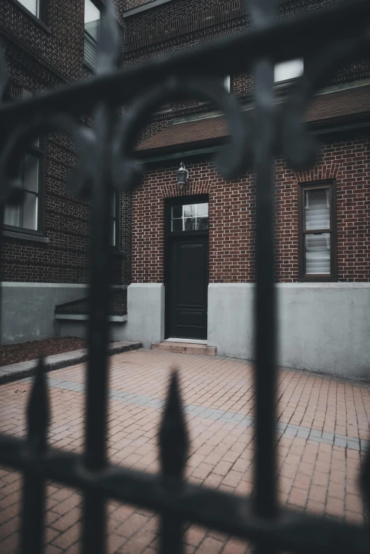 an empty brick courtyard in front of a black metal gate