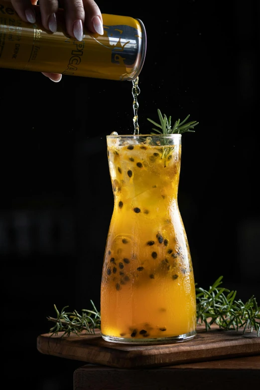 a beverage is poured into a glass with herbs