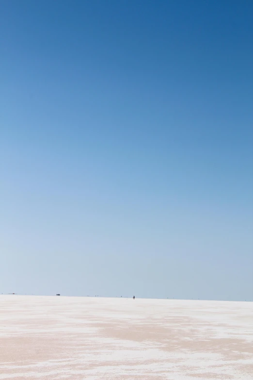 a man standing on a large empty beach next to a kite