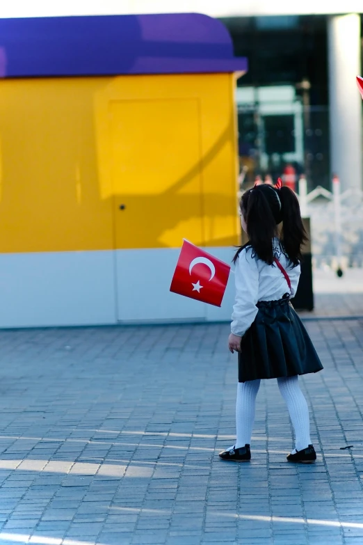 a  in a school uniform standing on a sidewalk