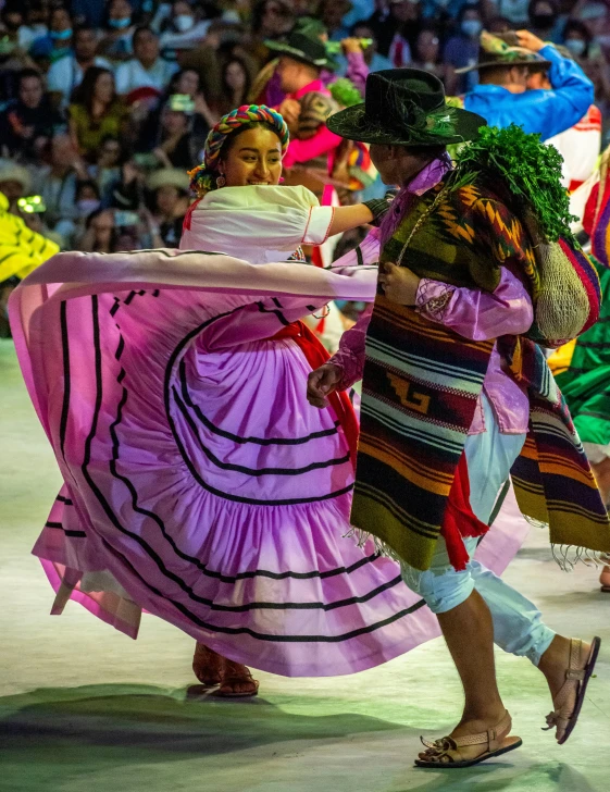 women in colorful dresses are dancing around with a group of people in the background