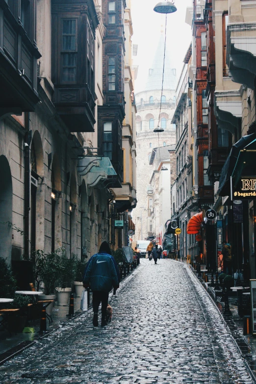 an empty street with a few people walking and a building in the back ground