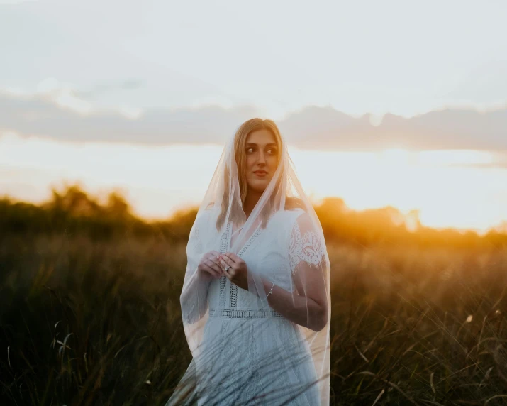 woman in white veil walking through tall grass
