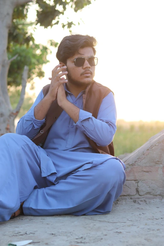 a man sitting on a rock talking on his cellphone