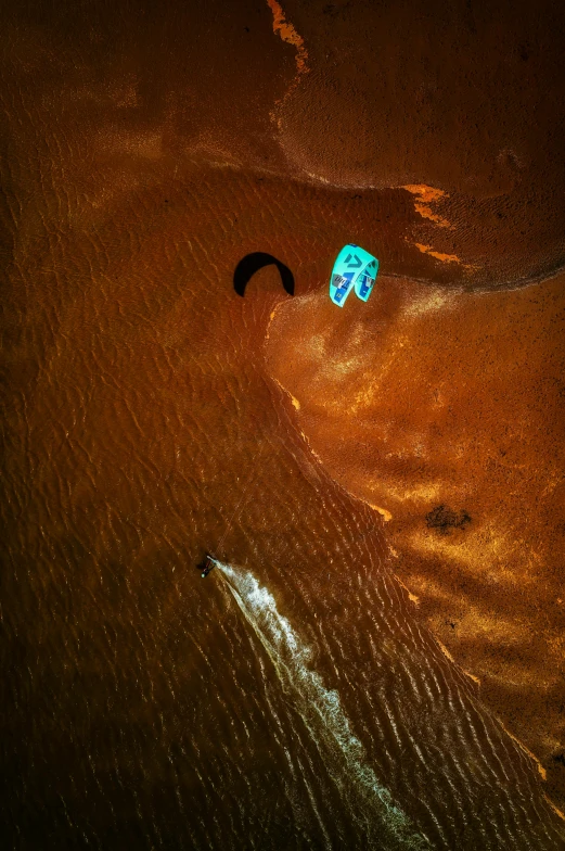 a kite is floating out on a dark sandy beach