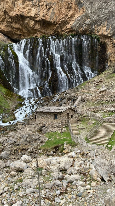 an old building with stairs and a waterfall in the background