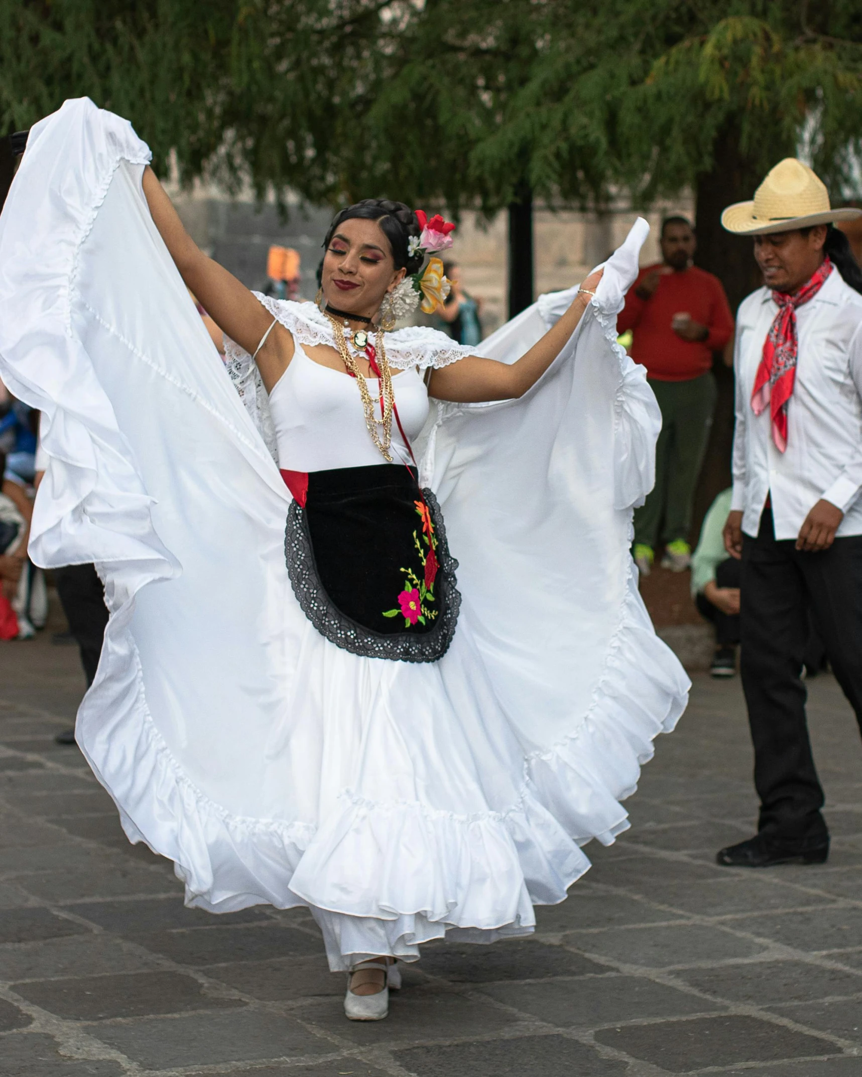 a woman dressed in a white mexican outfit dances