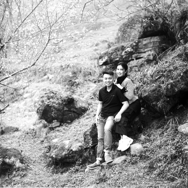 a couple of people sit together in front of a hill