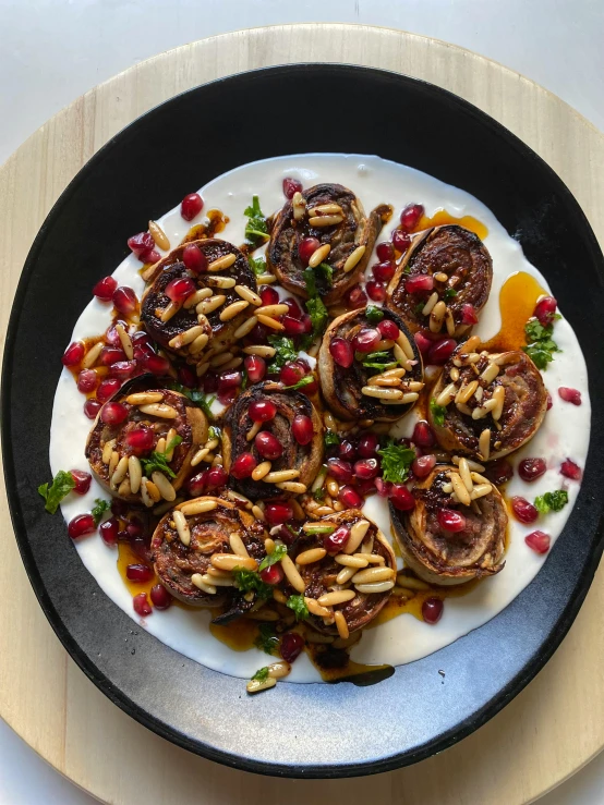 a black and white plate has mushrooms, tomatoes and pomegranates on it