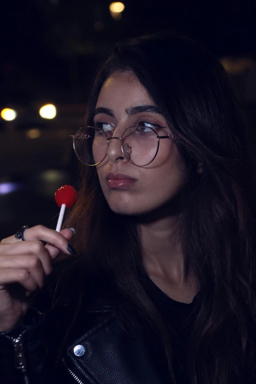 a woman is dressed up in black holding a candy lollipop