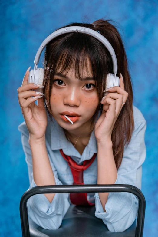 a woman poses with headphones and a suitcase