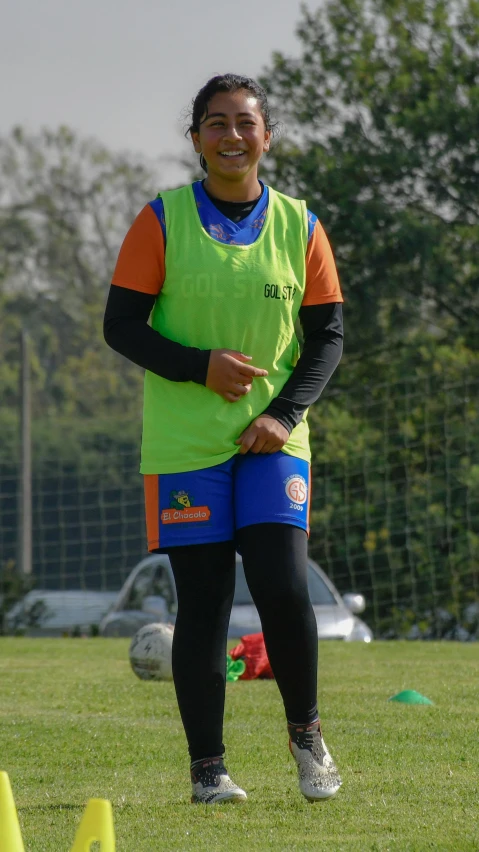 a girl with a colorful shirt and a black pants is standing on the soccer field