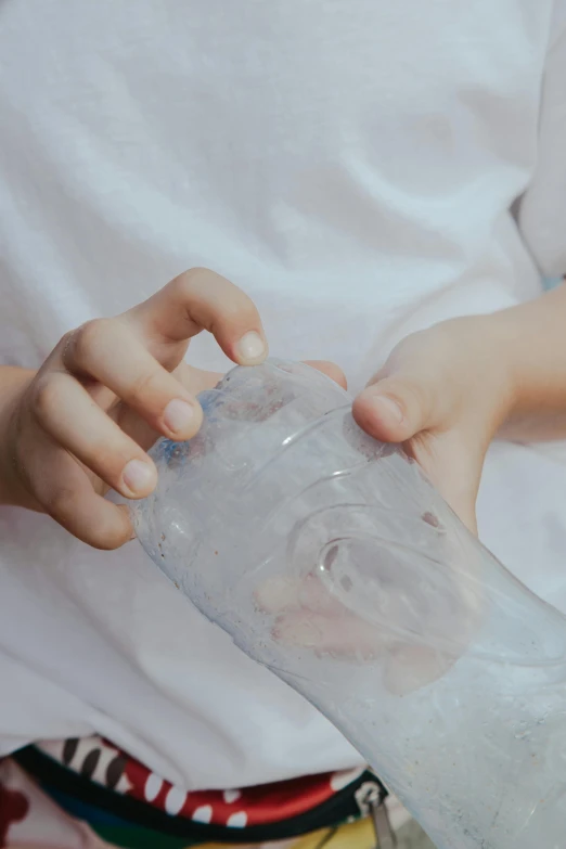 a close up of a person holding a plastic bottle with soing in it