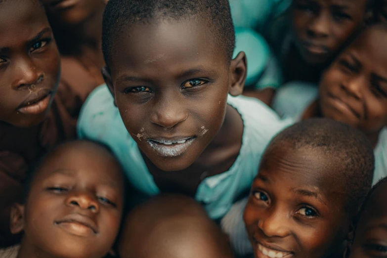 many children smiling and lying together while one is on the floor