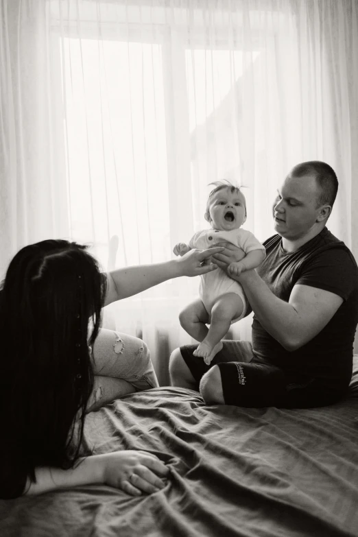 a man is sitting on the bed holding his baby