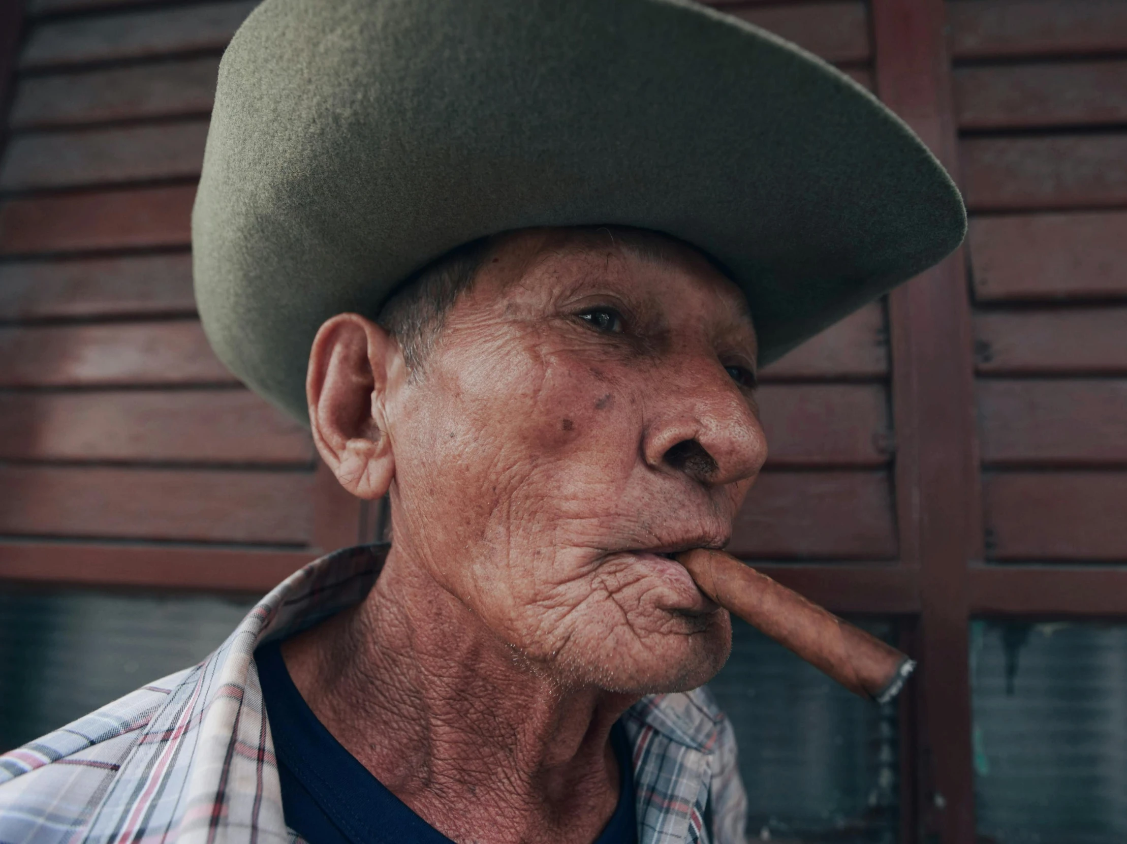 a man with a hat on his head is smoking a cigar