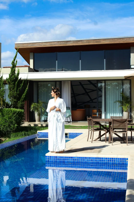 a woman standing on the deck of a house next to a pool