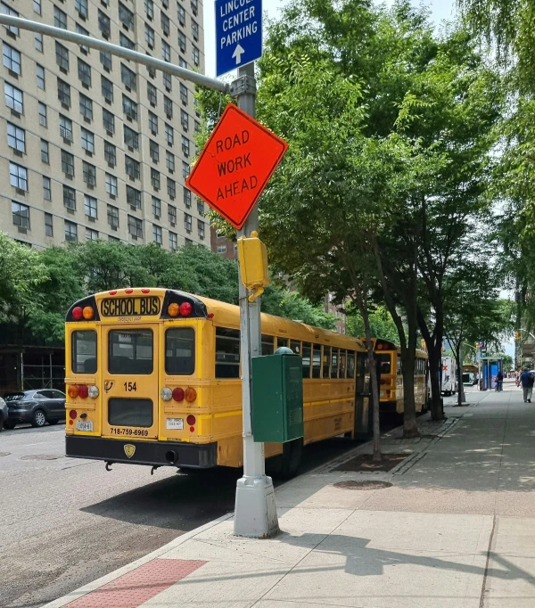 the school bus is stopped at the curb with the sign