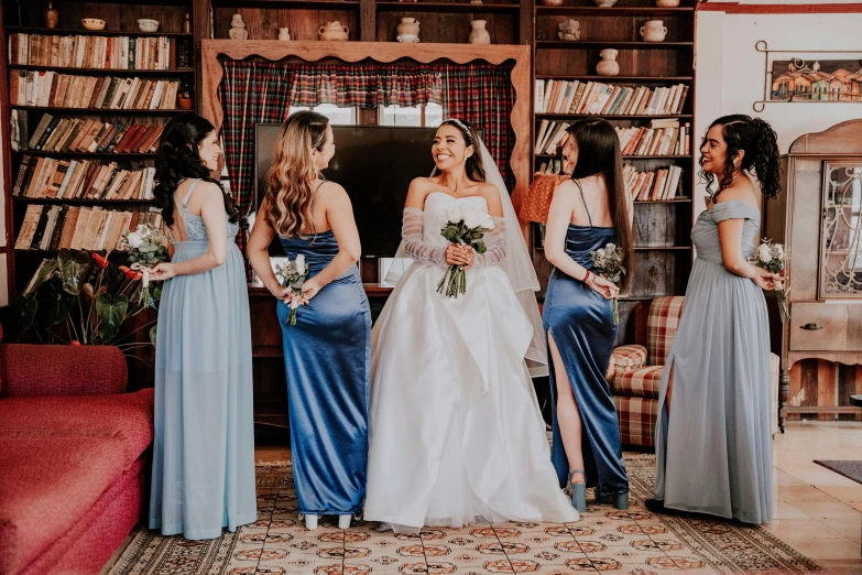 four women in long dresses are standing around