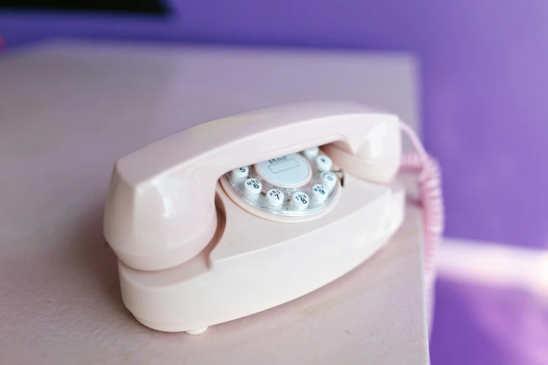 an antique pink phone on the counter in a bathroom