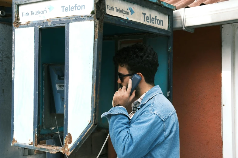 a man talking on his cell phone outside a payphone booth