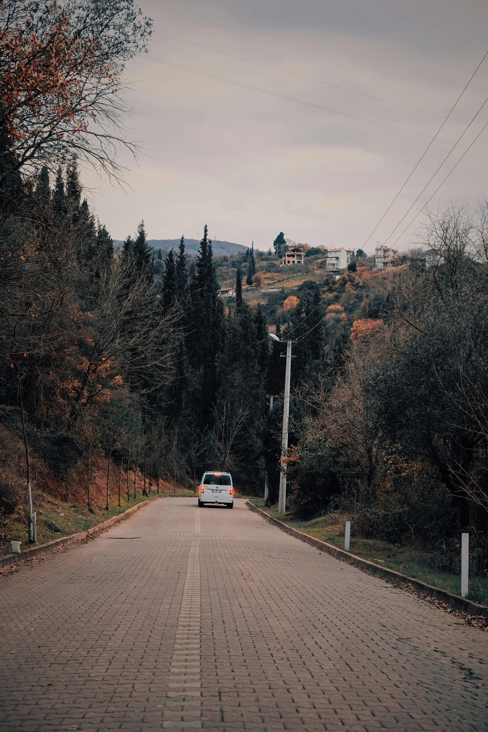 an old car sitting at the end of a dirt road