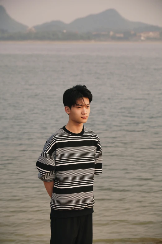 a young man stands in front of the ocean