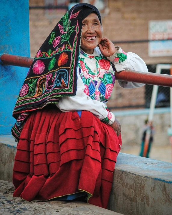 an elderly woman wearing a colorful head scarf and talking on the phone