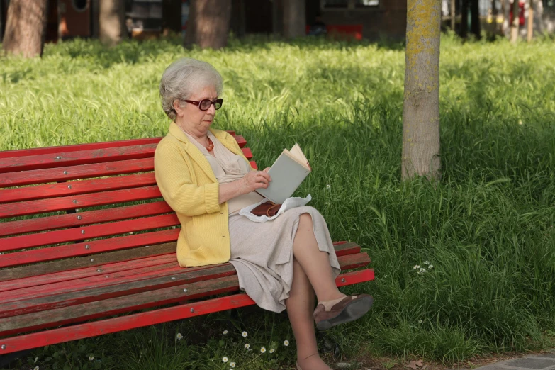 an old woman sitting on a bench reading a book