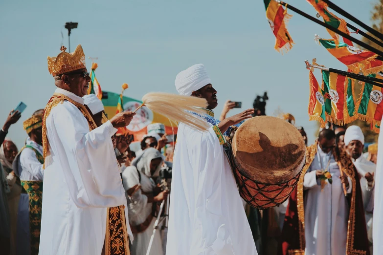 people dressed in white holding colorful ceremonial hats