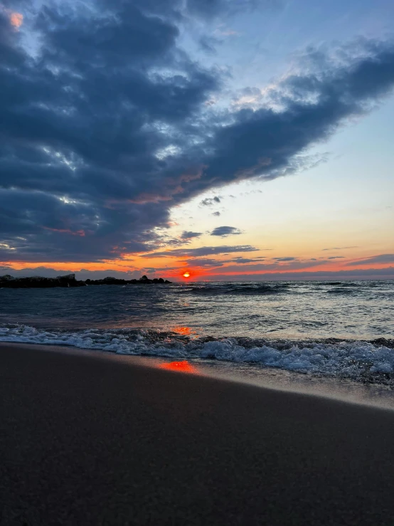 a sunset on the beach with dark clouds