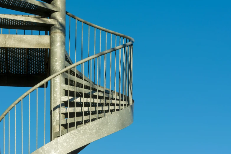 the bottom side of a metal staircase against a clear blue sky