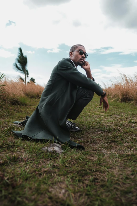 the man is sitting on the grass talking on his cellphone