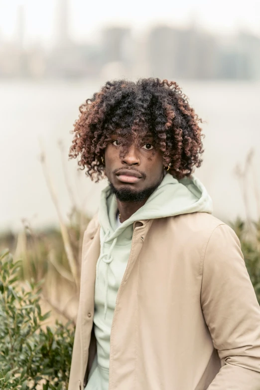 a black man standing near some bushes