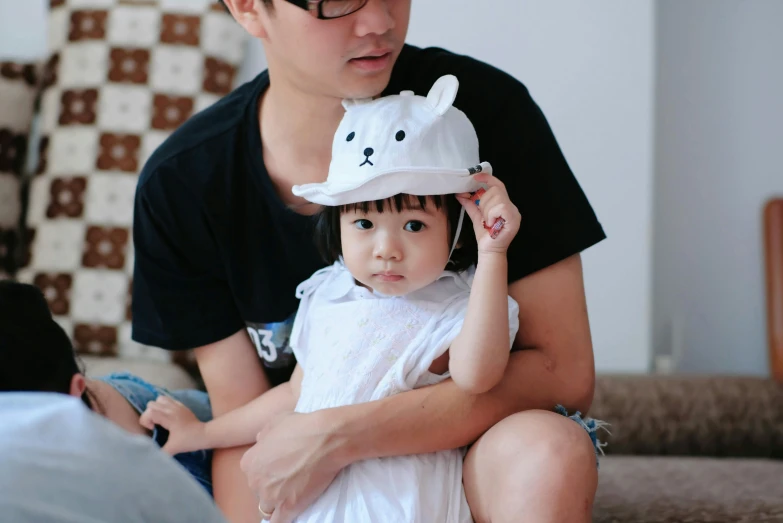 a man holding a baby wearing a hat that has a bear on it