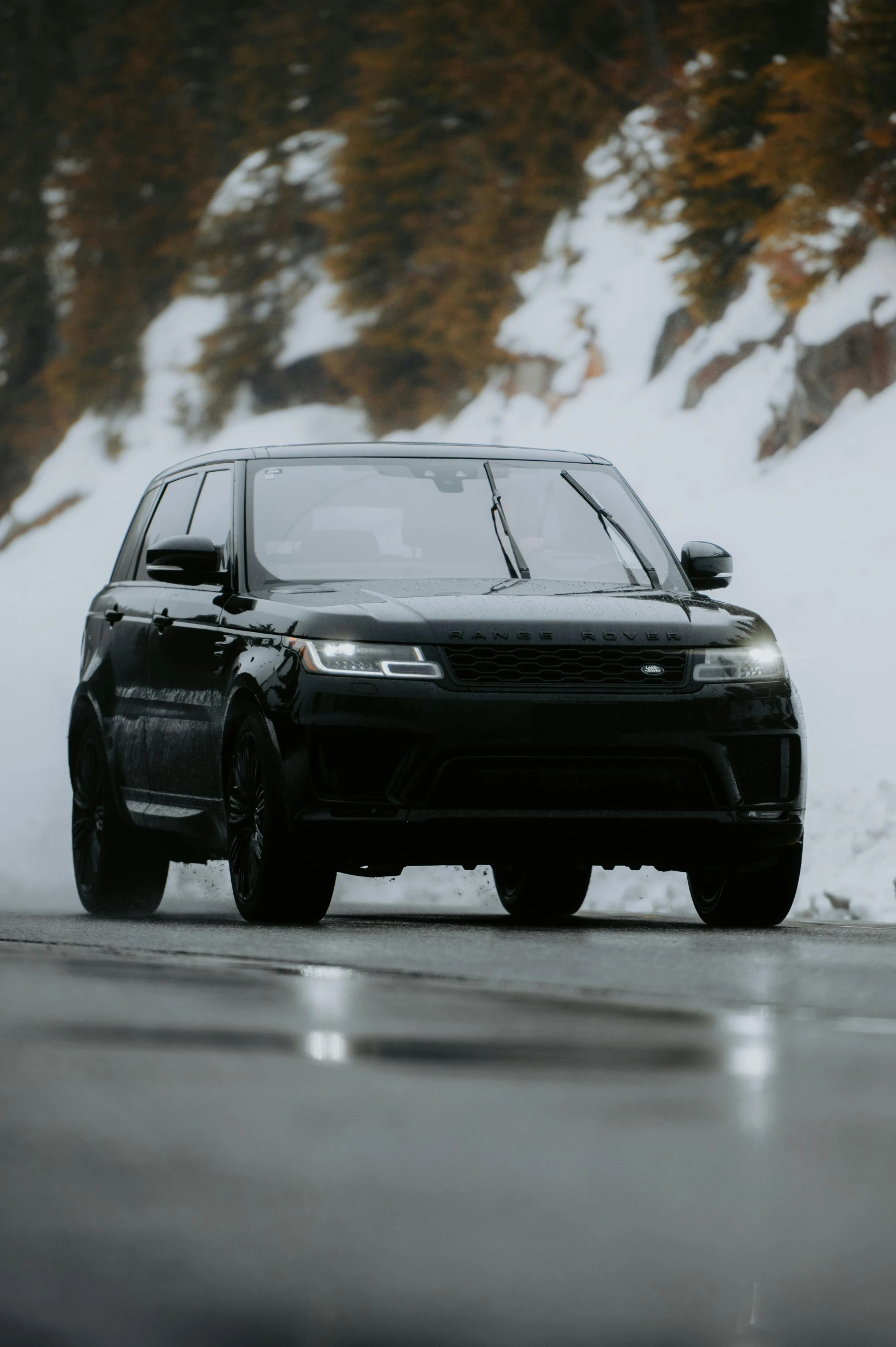 a black car driving on a snow covered road