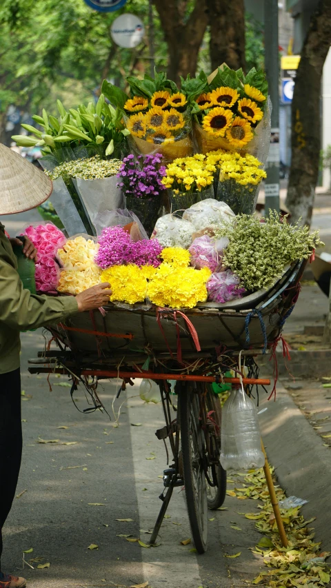 the bicycle is carrying many flowers on the sidewalk