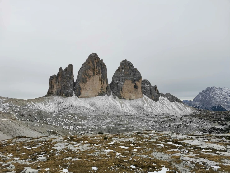 a group of mountains covered in snow with green grass