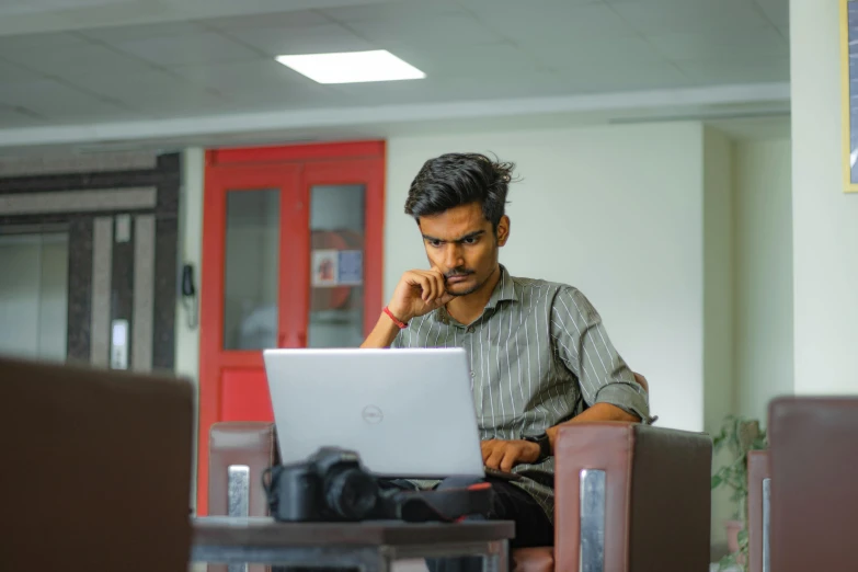 a man sitting in a chair while looking at a laptop