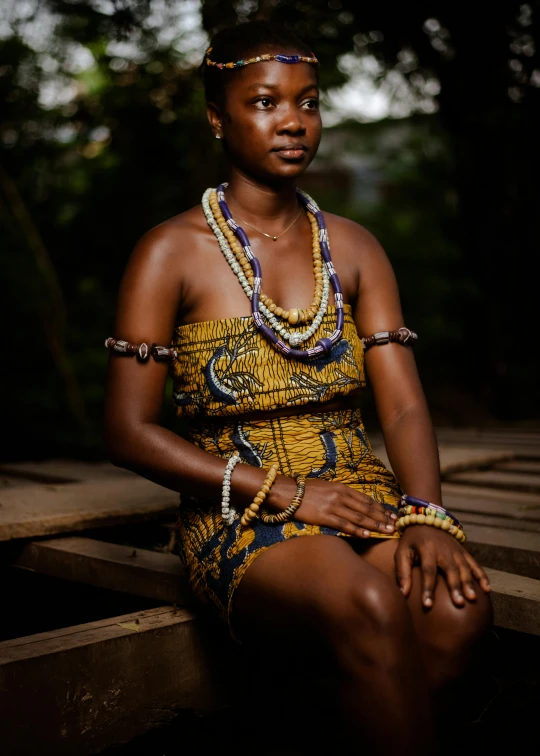 a woman in a short yellow dress sitting on a wood plank