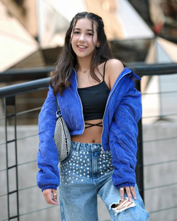a young woman in blue jacket and jeans looking at the camera